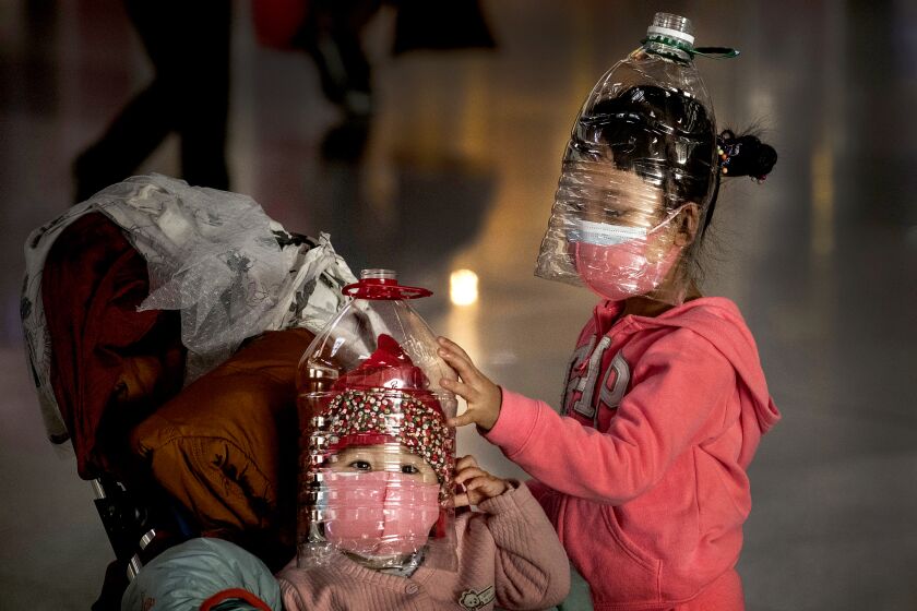 CHINA: Chinese children wear plastic bottles as makeshift homemade protection and protective masks while waiting to check in to a flight at Beijing Capital Airport in Beijing, China.