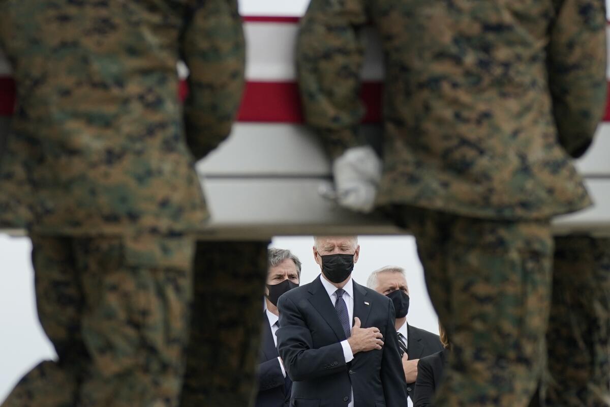 President Biden watches with hand over heart as the body of a Marine is carried by.