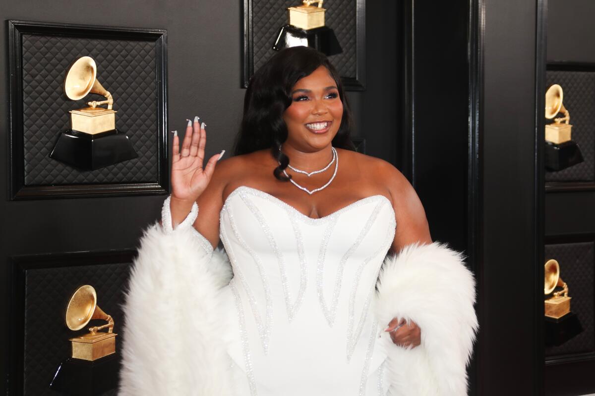 A woman smiling and waving in a white dress