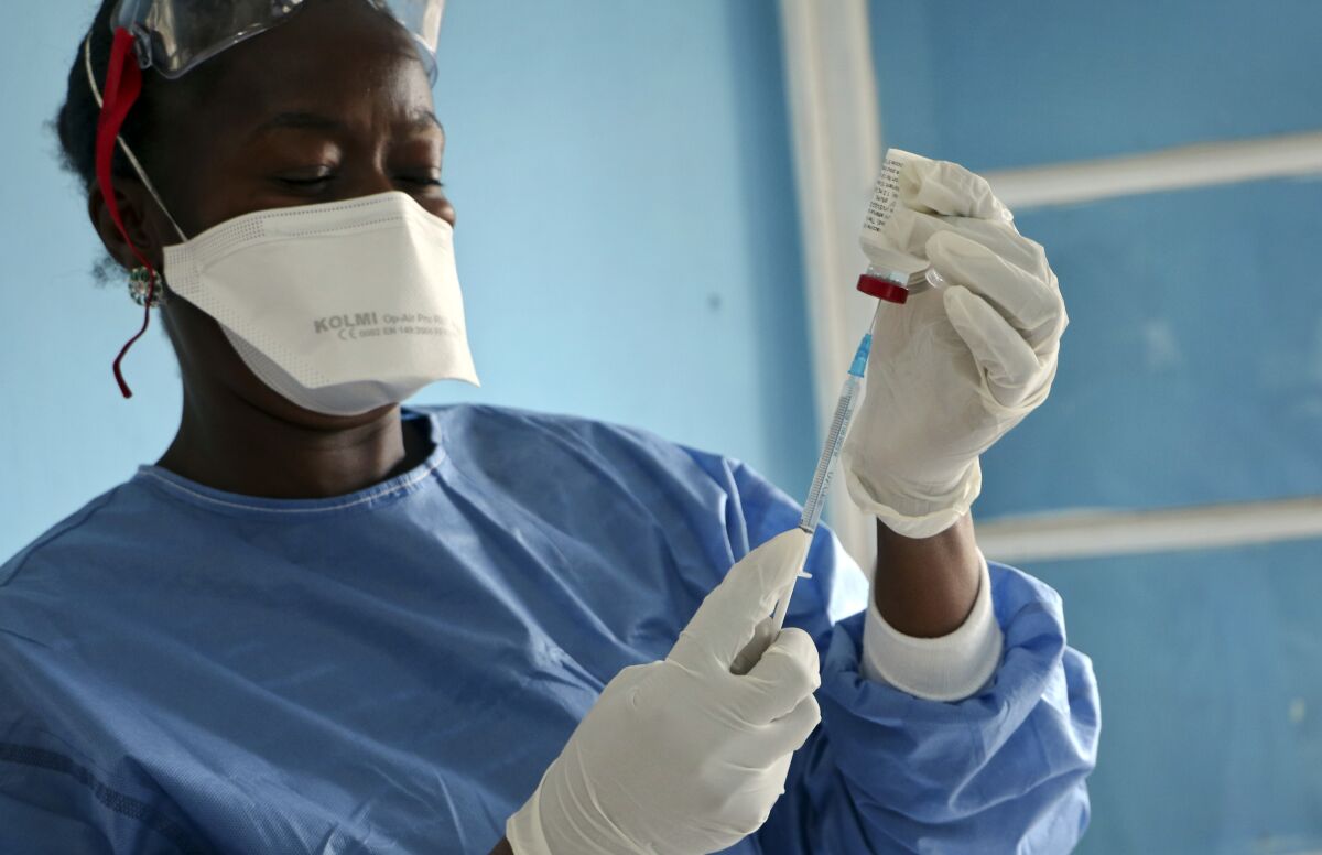 A healthcare worker wearing personal protective equipment prepares an injection