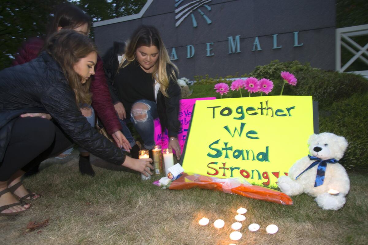 Ariel Pantoja, 19, left, Bayley Morrow, 18 and Makayla Bentley, 18, light candles at a makeshift memorial outside the Cascade Mall on Sept. 24, 2016, in Burlington, Wash.