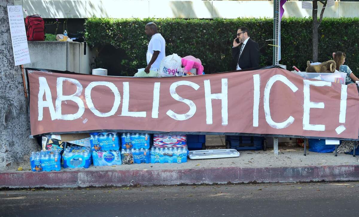 A banner reading "Abolish ICE" is displayed as immigrant rights advocates pitch their tents for an encampment outside the ICE offices in downtown Los Angeles on June 28.