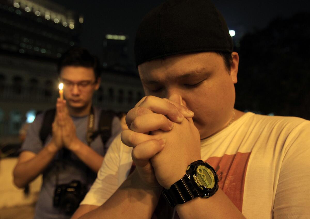 Men offer prayers during a candlelight vigil Monday in Kuala Lumpur, Malaysia, for passengers aboard a missing Malaysia Airlines plane.