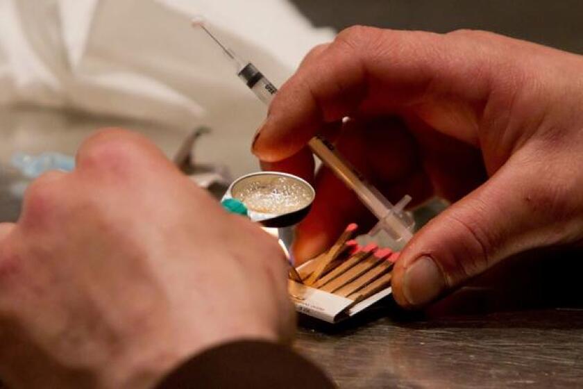 A man prepares heroin he bought on the street to be injected at the Insite safe injection clinic in Vancouver, Canada.