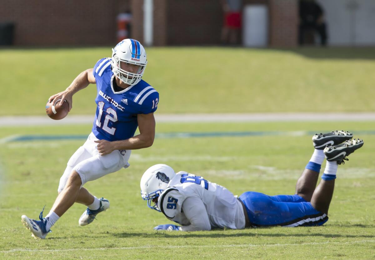 Presbyterian quarterback Ren Hefley (12) skirts the tackle of St. Andrews' Rashon Gholson (95) during a college football game, Saturday, Sept. 4, 2021, at Bailey Memorial Stadium in Clinton, S.C. (Sam Wolfe/The State via AP)