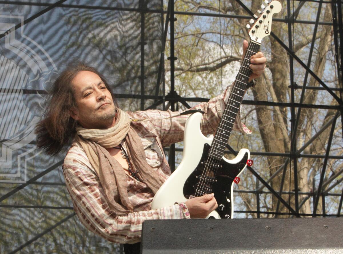 Guitarist Jake E. Lee lifts his guitar while playing onstage outdoors