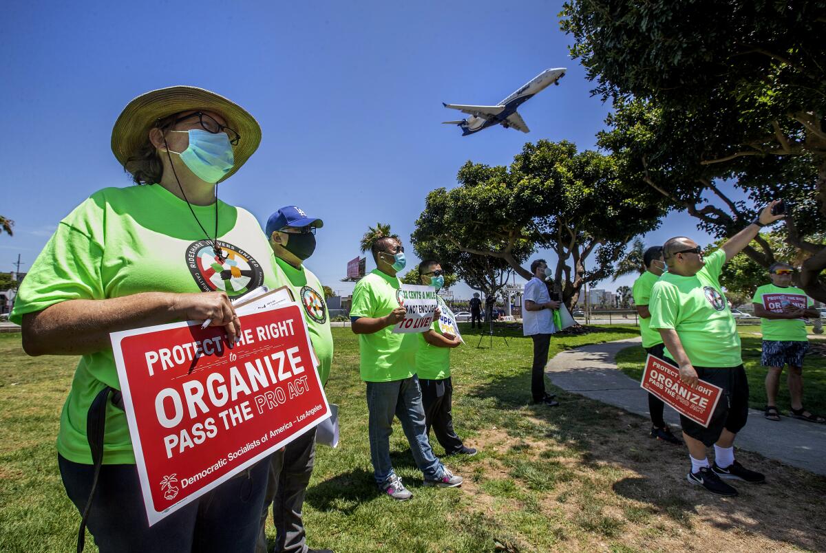 Nicole Moore, left, a driver for Lyft, joins other rideshare drivers during a rally at LAX.