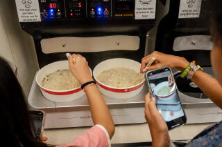Shoppers prepare their dinner at one of the self-serve machines in the dining area at a CU ramyon convenience store.