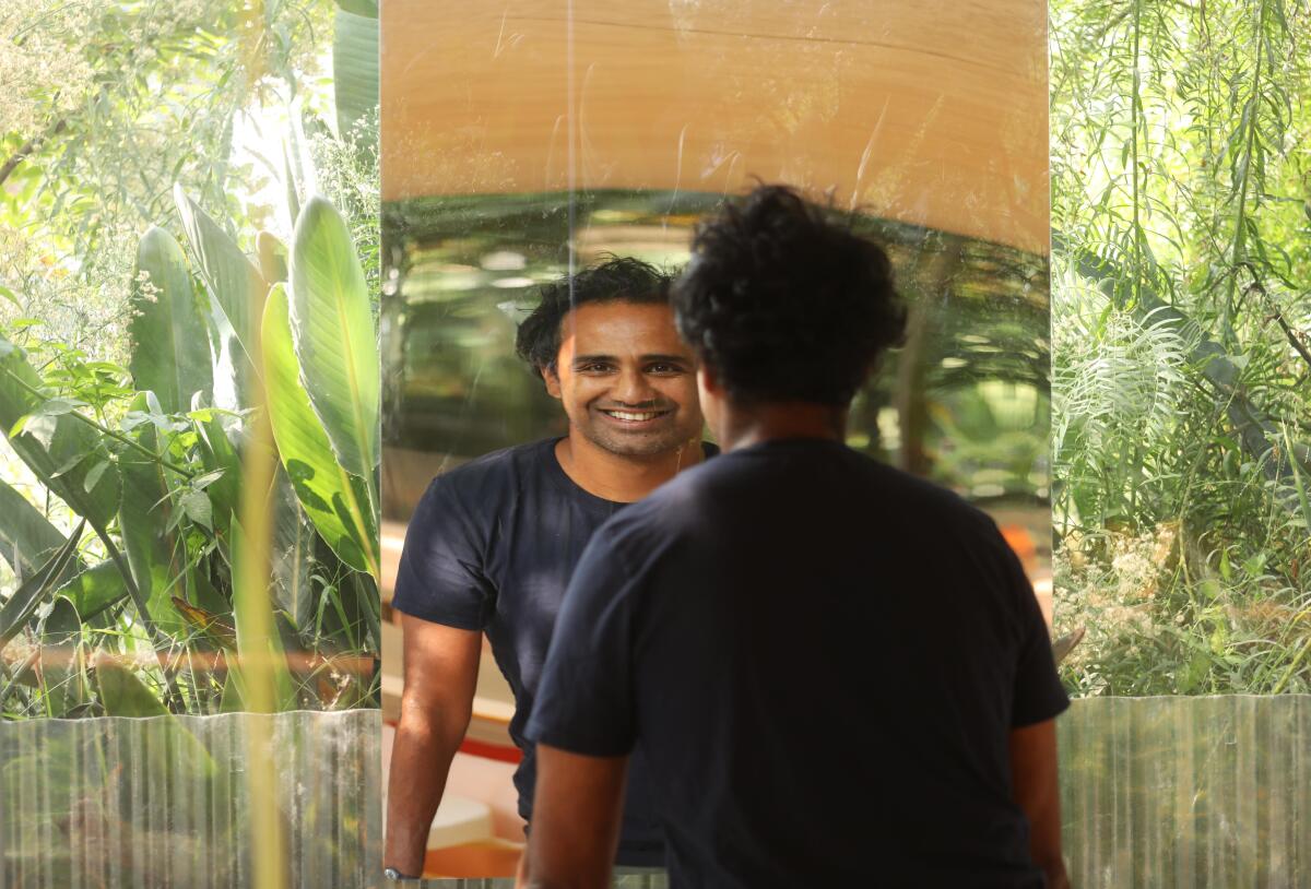 Rohan Silva is reflected in the mirror of one of the garden studios at Second Home in Hollywood.