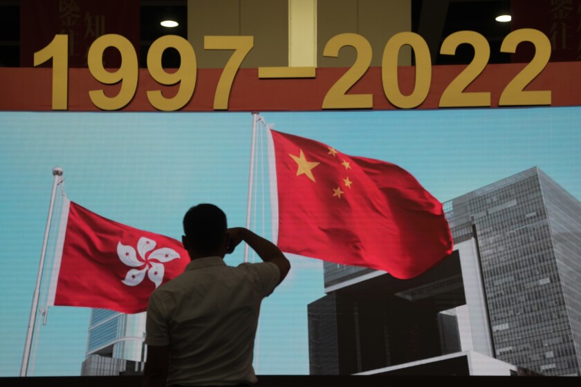 Silhouette of man beneath Chinese and Hong Kong flags