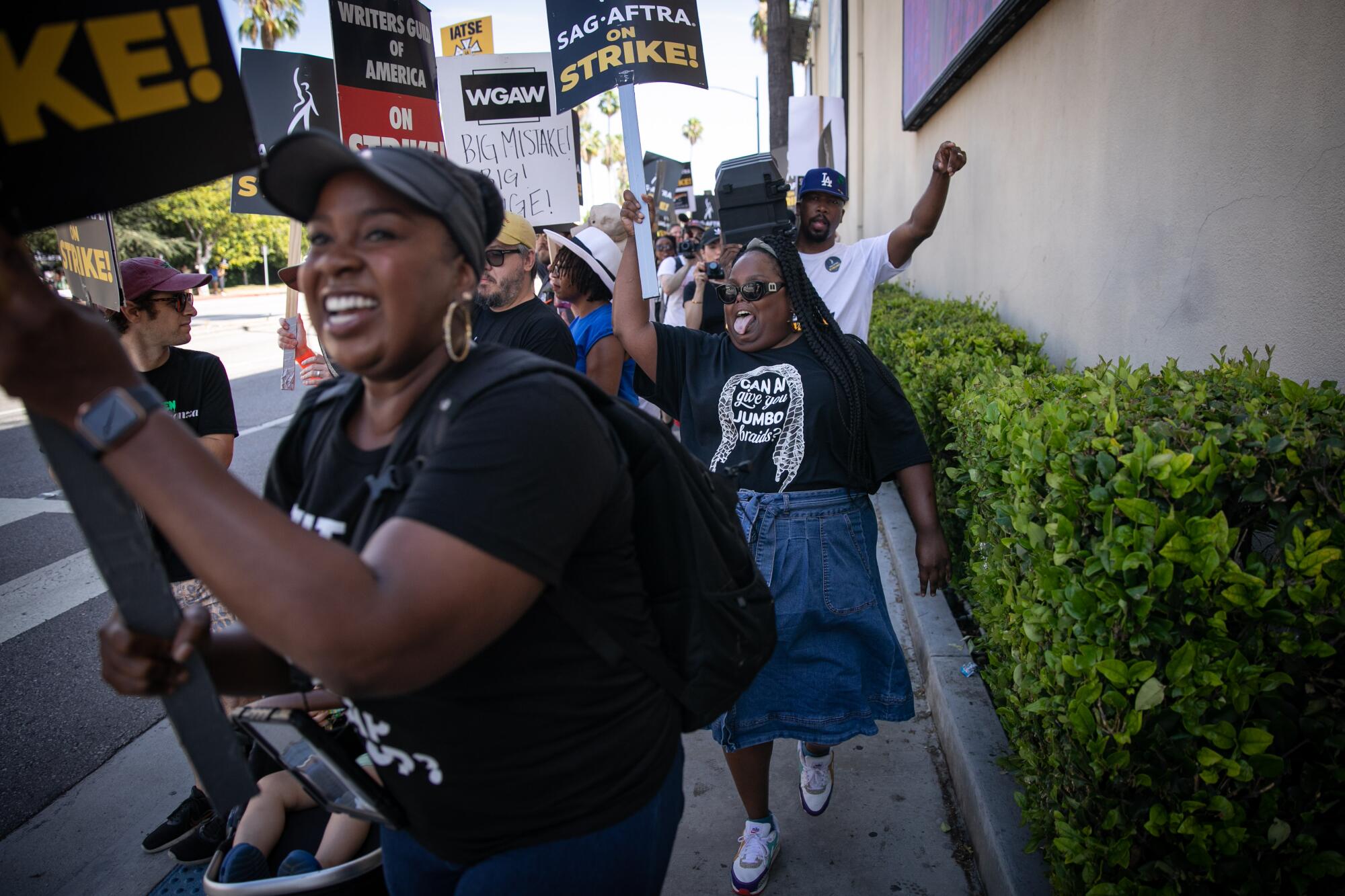 Black women marching with picket signs during writers' strike