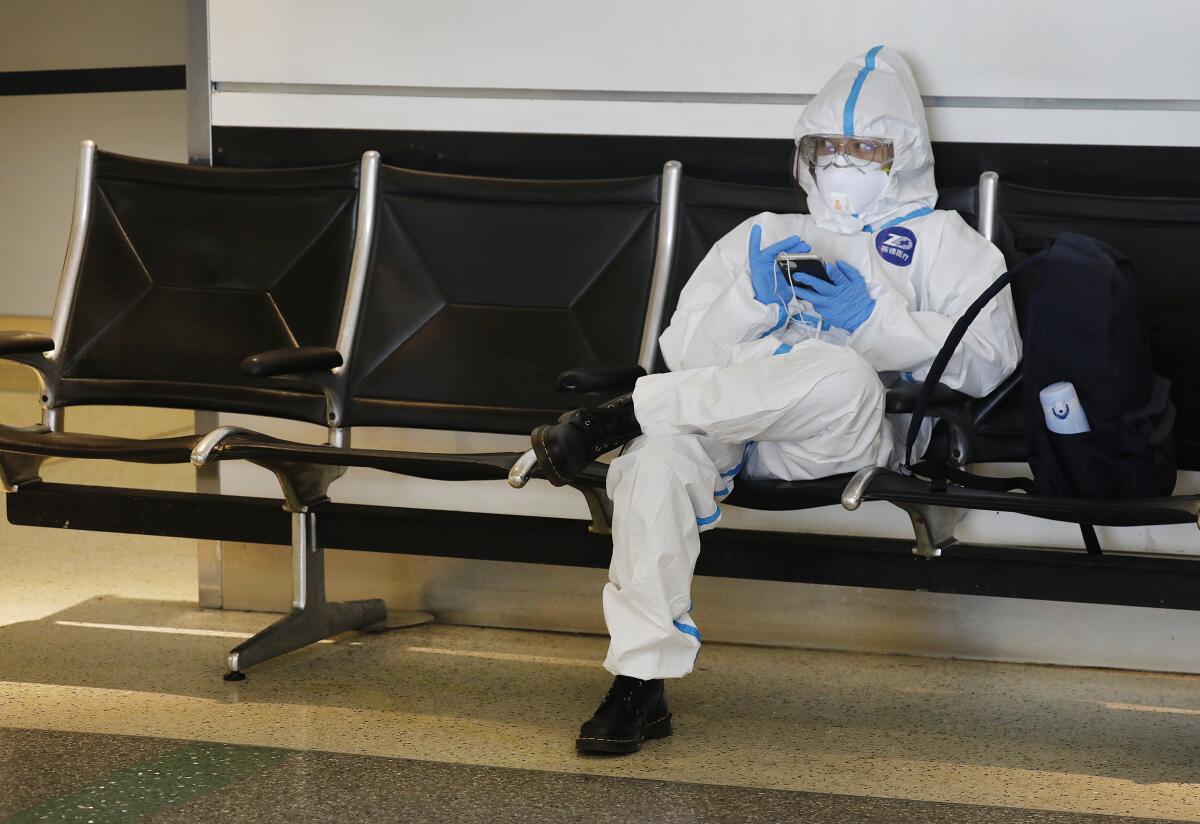 A Chinese student wearing protective gear waits for a flight home at Los Angeles International Airport in May.