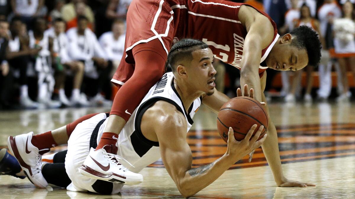 Oklahoma State guard Jeffrey Carroll looks to pass while under pressure from Oklahoma guard Jordan Shepherd, right, reaches for the ball held by during the first half Saturday.