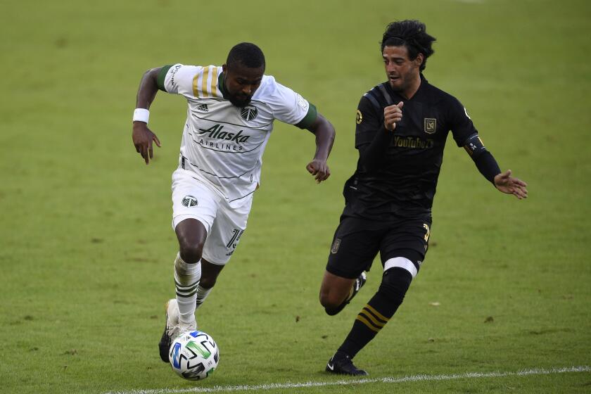 Portland Timbers defender Chris Duvall, left, moves the ball while pressured by Los Angeles FC forward Carlos Vela.