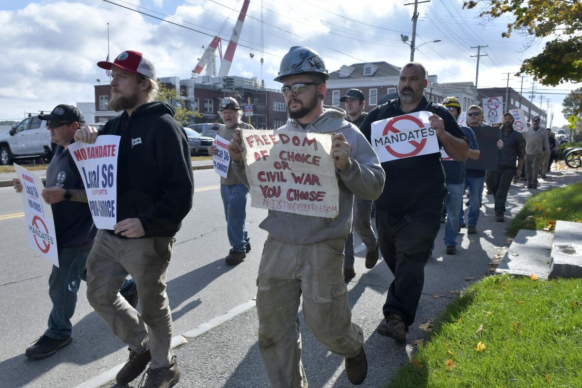 Several men take part in a demonstration against a COVID-19 vaccine mandate outside a shipyard on Friday. 