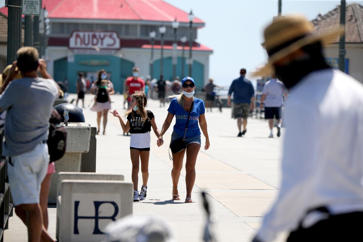 Visitors to the pier wear face masks, in Huntington Beach on Friday, July 31, 2020.