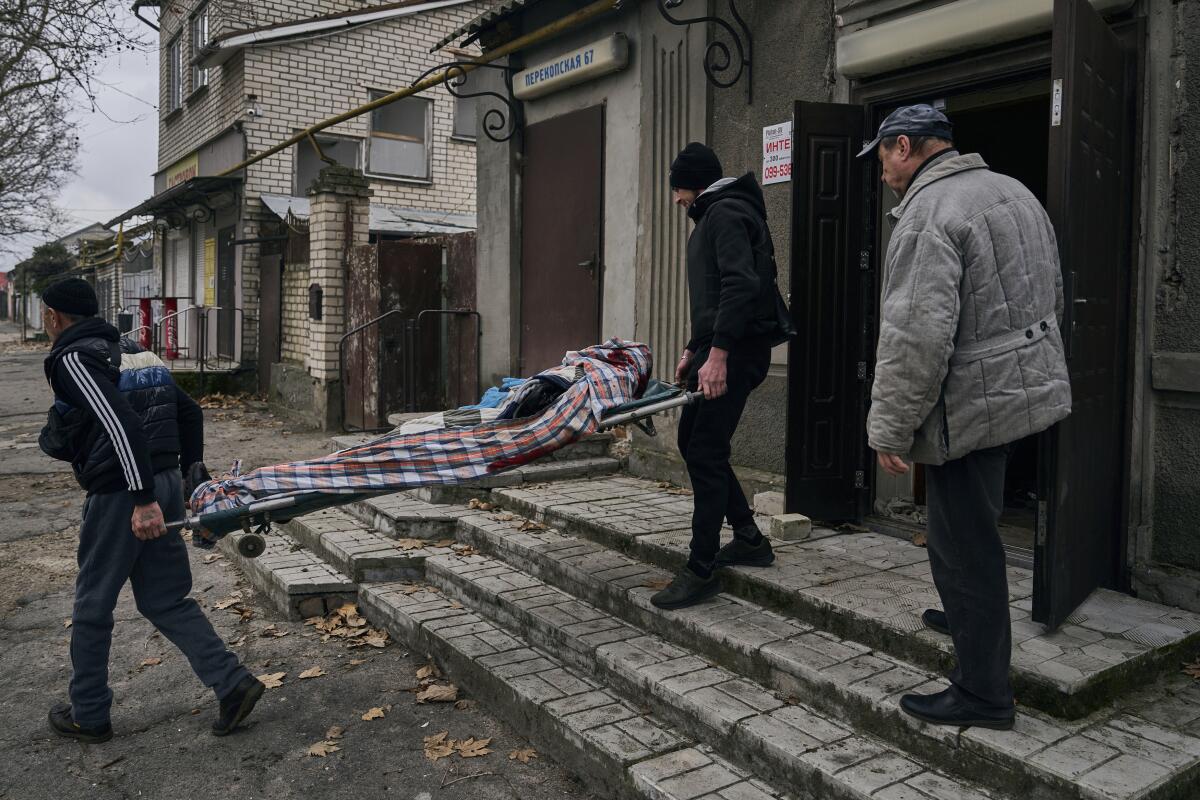 Civiles ucranianos cargan el cuerpo de un hombre de 20 años que murió en un bombardeo ruso