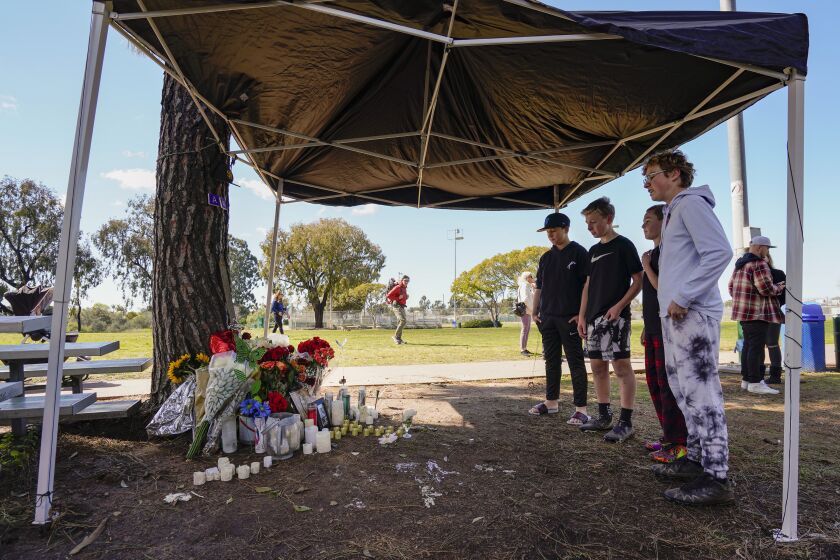 SAN DIEGO, CA - FEBRUARY 26: From foreground, Austin Johnstone, 13, Bradley Eby, 12, Jack Fabrega, 13, and Keegan Mann, 11, background, pause at the memorial setup for Cesar Lopez-Sandoval, 22, in the park, at the North Clairemont Recreation Center, near where he was gunned down February 19. Three of the four were in the park at the time of the shooting, Bradley, Jack, and Keegan. Photographed February 26, 2023, during the "Take Back the Park" vigil, organized by Clairemont resident Mike Pallamary. (Howard Lipin / For The San Diego Union-Tribune)