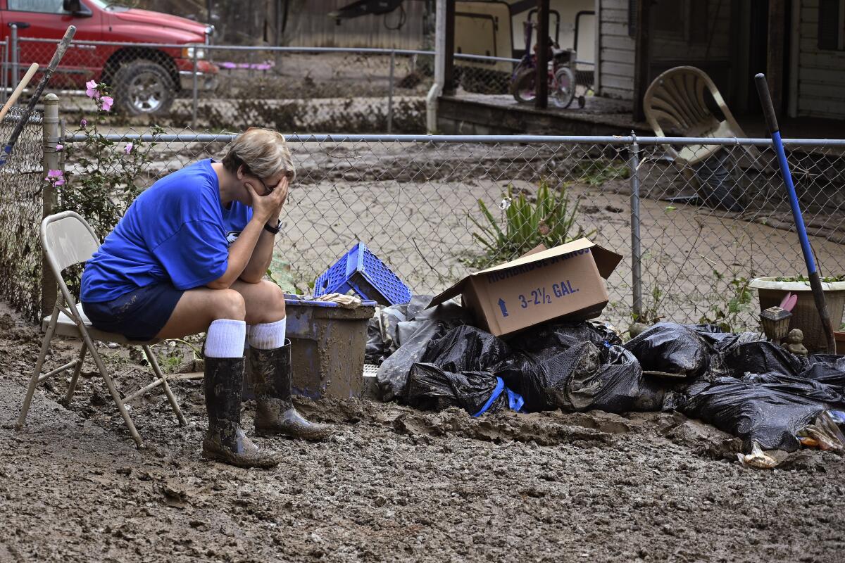 Teresa Reynolds se sienta exhausta mientras miembros de su comunidad despejan los escombros 