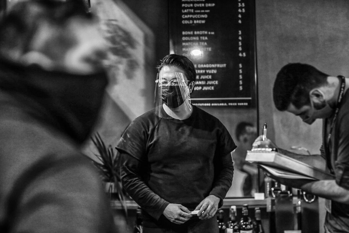 Eric Tjahyadi wears a face shield as he talks to health inspectors at Bone Kettle.