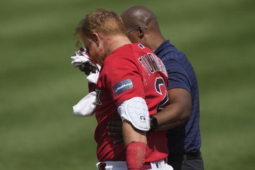 Boston Red Sox Justin Turner is walked off the field after being hit in the face on a pitch.