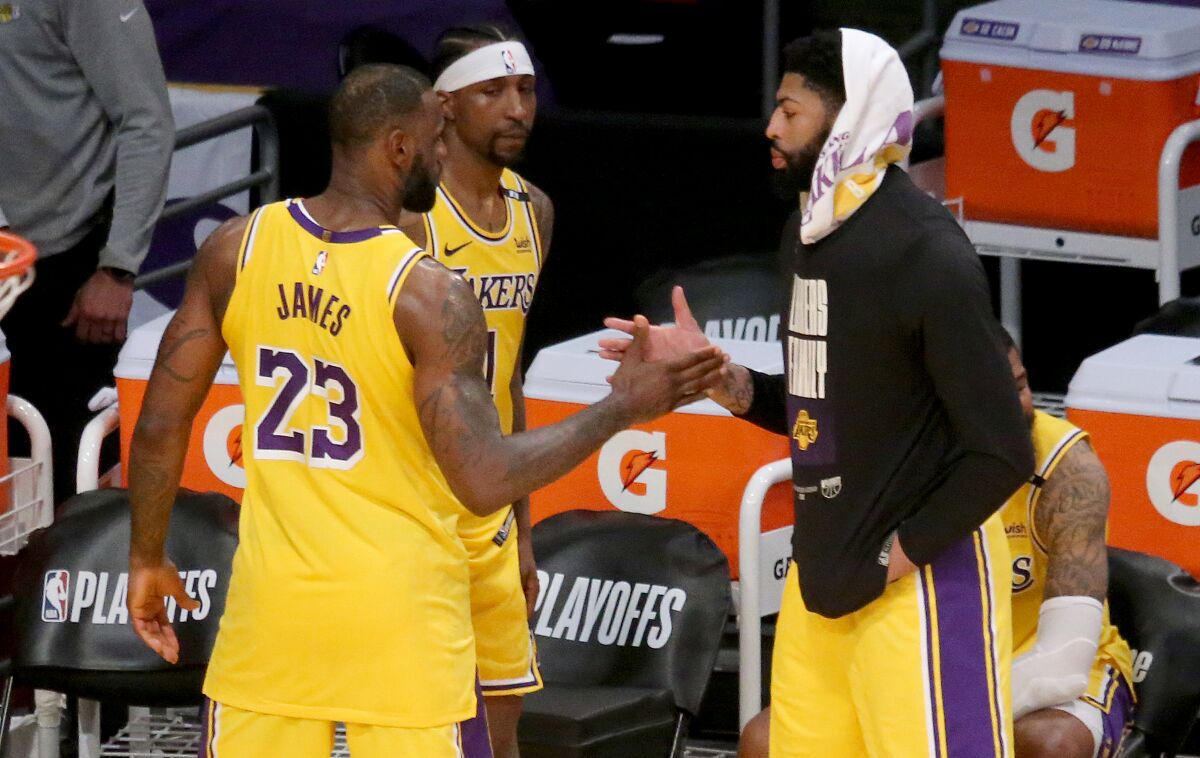 On the sideline, LeBron James and Anthony Davis reach out to clasp hands.