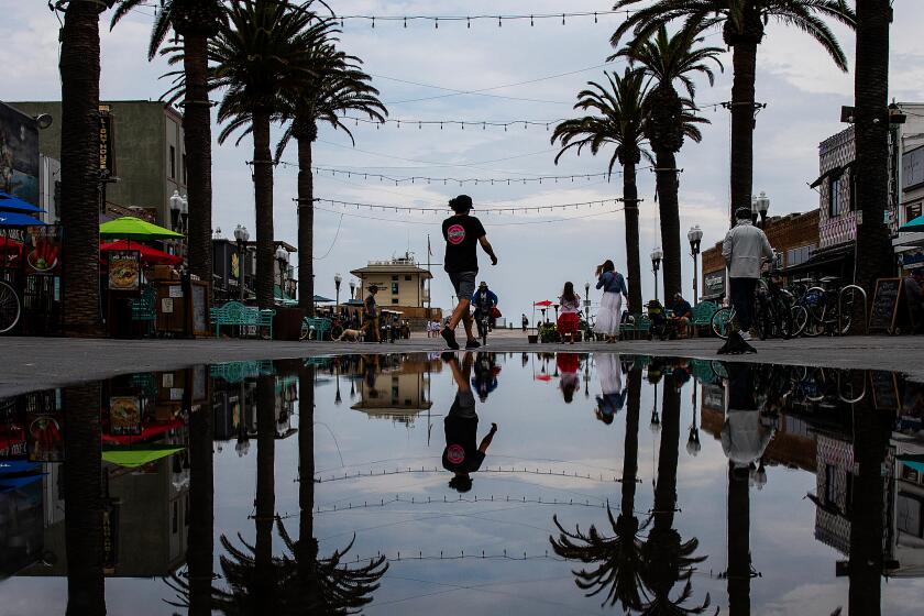 A pedestrian is reflected in a puddle in Hermosa Beach on Monday after rain passed through the area.