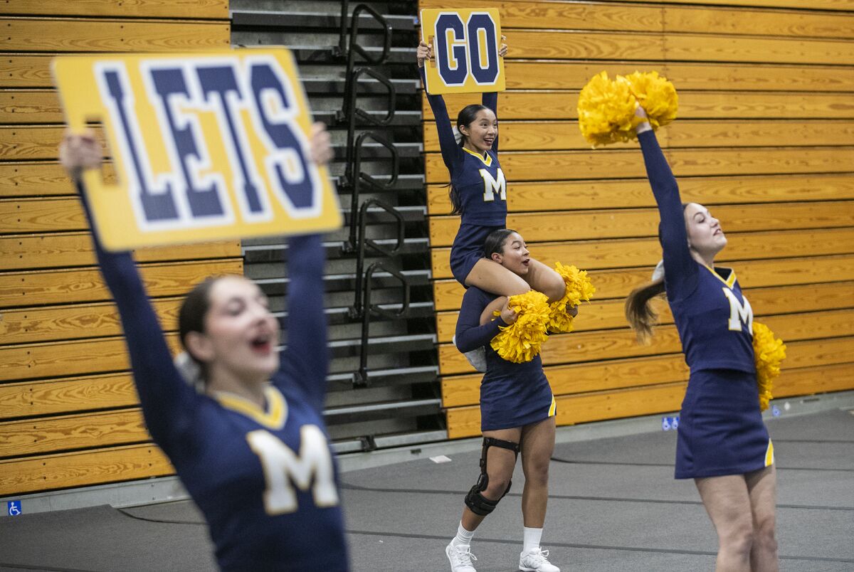 Maleah Gamblin, center, flies Dorsey Tran on her shoulders during Marina High cheerleading team practice.
