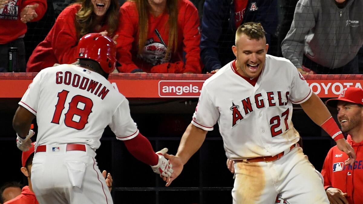 Brian Goodwin is greeted at the dugout by Mike Trout after hitting a solo home run in the eighth inning against the Toronto Blue Jays at Angel Stadium on April 30, 2019.