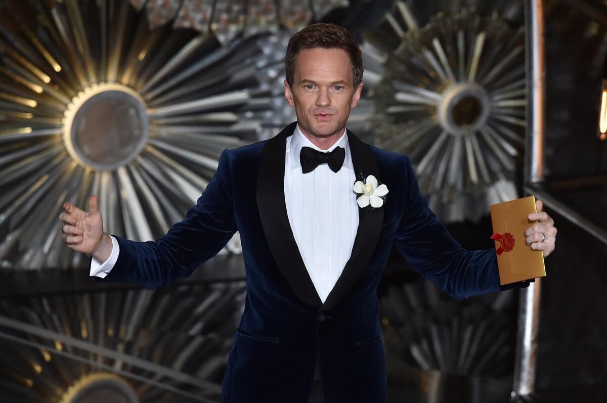 Host Neil Patrick Harris in a navy blue velvet shawl-collar tuxedo by Tom Ford, the last of five tuxedos he wore at the 87th Academy Awards.