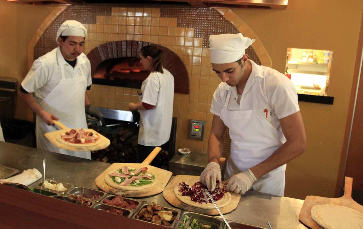 Pizzas are prepared in a wood-burning oven.