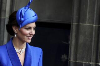 Kate Middleton wears a bright blue blazer and fascinator as she looks out in front of a large door