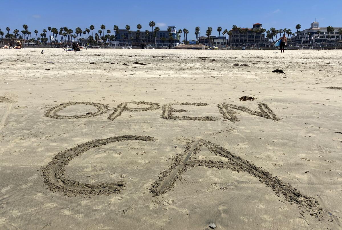 Someone wrote "Open CA" on the sand just before the "Live Free Protest to Open CA." event started at Main and Pacific Coast Highway in Huntington Beach on Friday.