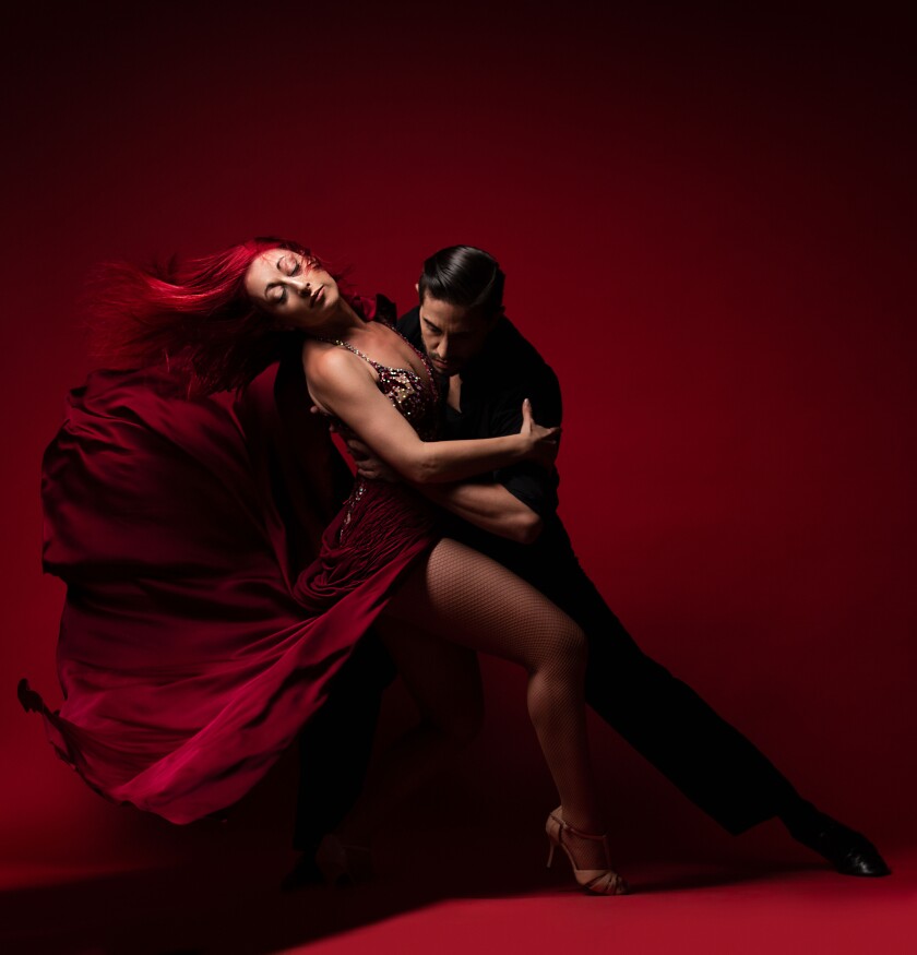 Ivana Ayala, in a flowing red dress, dances the tango with partner Pedro Sanchiz.