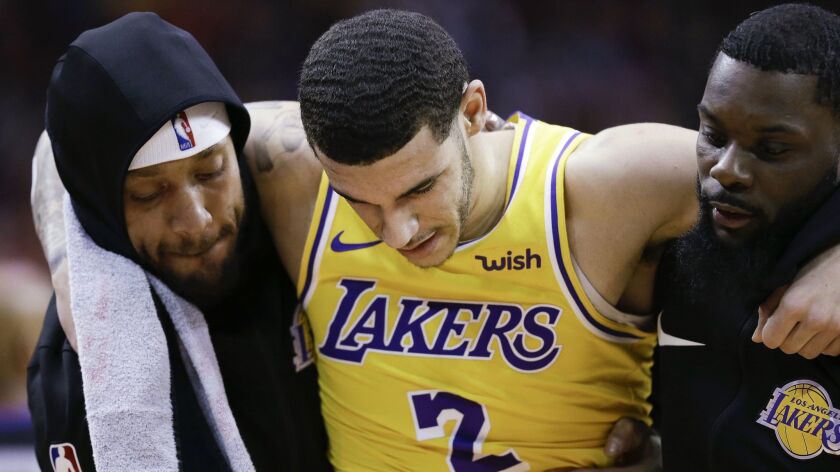 Lakers guard Lonzo Ball, center, is carried off the court by Michael Beasley, left, and Lance Stephenson after suffering a sprained ankle against the Houston Rockets on Jan. 19.