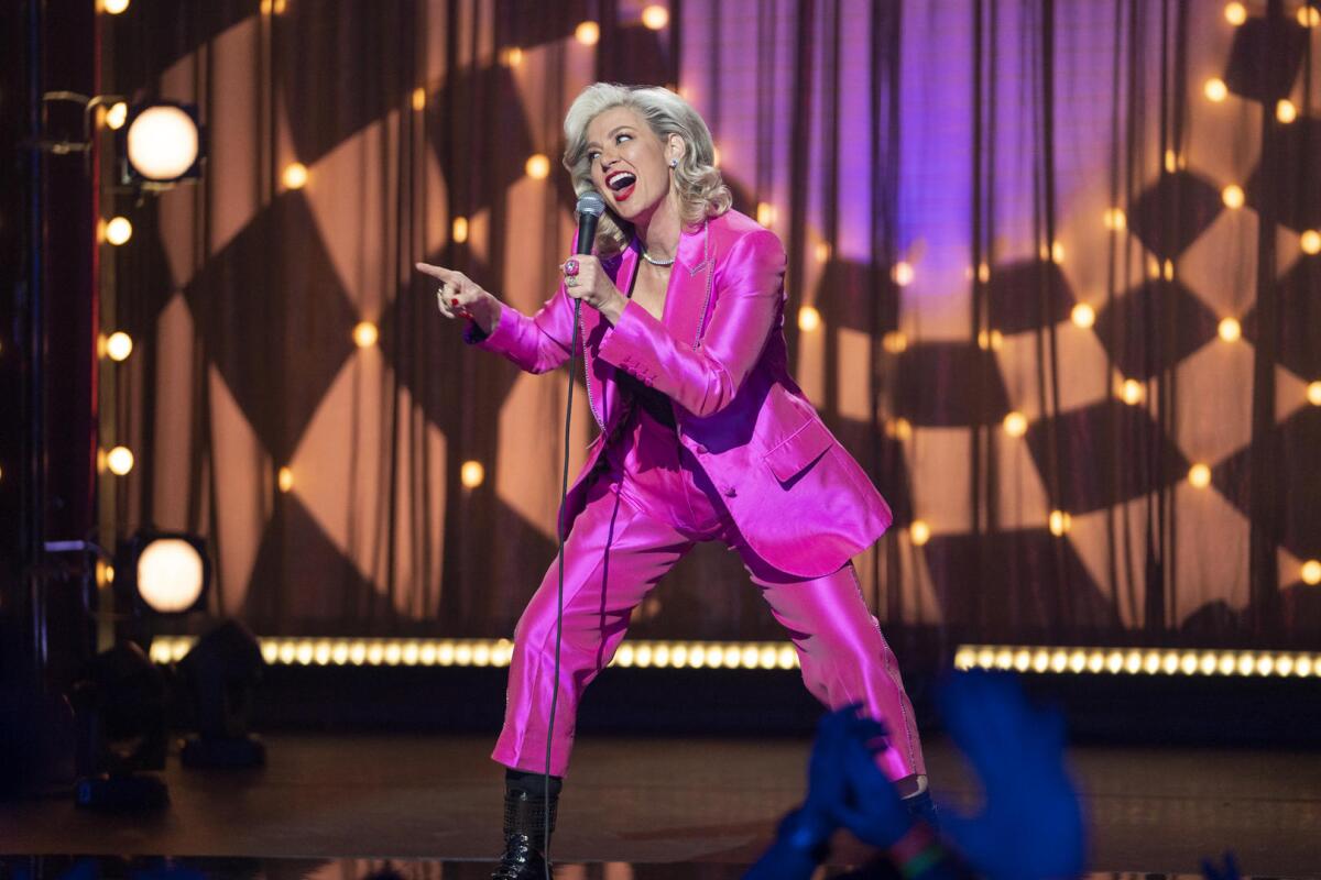 Comedian Christina P. holds a microphone while performing onstage