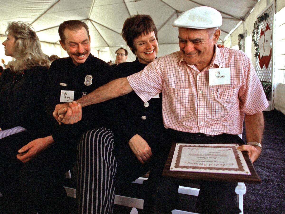 Los Angeles city Firefighter Mike Henry, left, takes the hand of Jerry Prezioso, whom he rescued from Northridge Meadows. Prezioso received a certificate of appreciation from Northridge Hospital Medical Center, where he was taken after the quake for treatment of his injuries, at a fifth anniversary ceremony in 1999. In the middle is Prezioso's friend Linda Chantland.