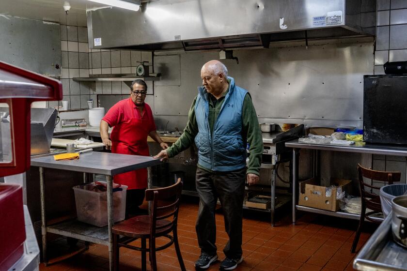 ANAHEIM, CA - MAY 3, 2023: Owner Samuel Solis talks with one of his chefs in the kitchen of his family owned restaurant Taco Boy which is one of Orange County's first taquerias on May 3, 2023 in Anaheim, California. The 45 year old restaurant has had a string of break-ins recently so they had to install metal bars on the front door and windows.(Gina Ferazzi / Los Angeles Times)