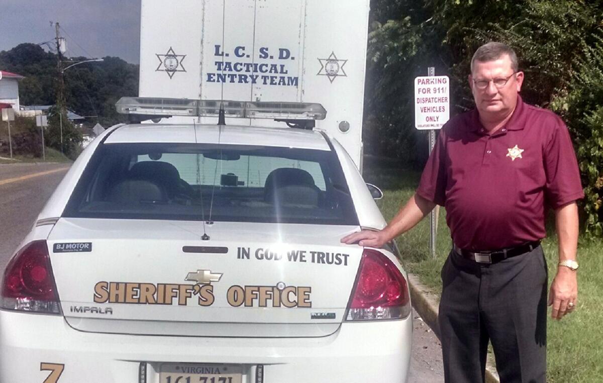 Lee County, Va., Sheriff Gary Parsons stands next to a patrol car that displays an "In God We Trust" decal. Parsons said his office spent a total of $50 to have the decals added to about 25 vehicles.