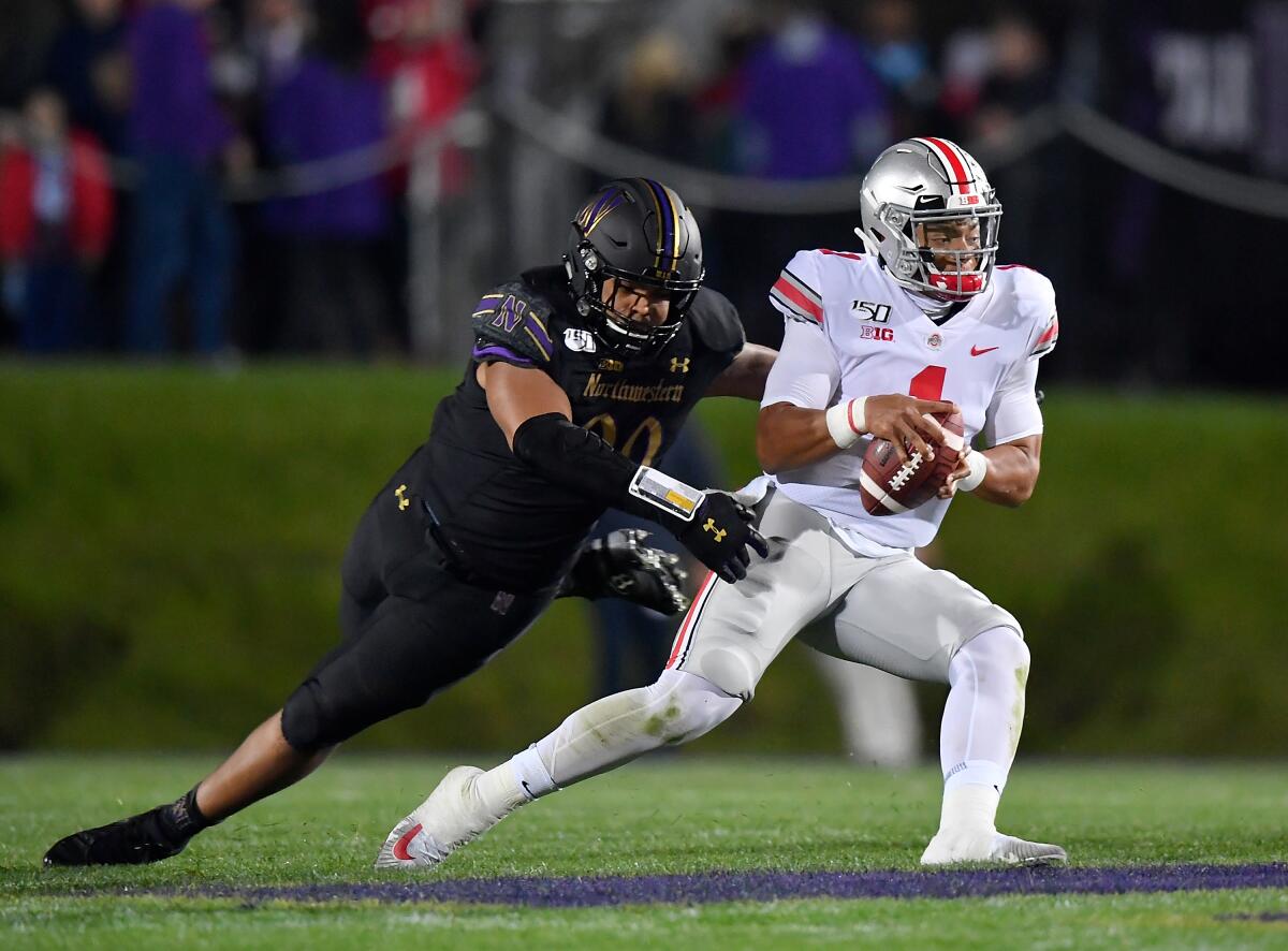 Ohio State's Justin Fields (1) scrambles in the second quarter to avoid a sack from Northwestern's Earnest Brown IV (99) on Friday in Evanston, Ill.