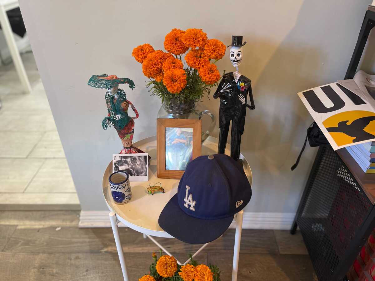 A table has framed photos, marigolds and a Dodger cap.