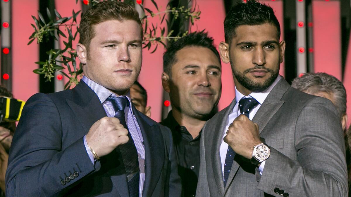 Boxers Canelo Alvarez, left, and Amir Khan, right, pose for a photo with promoter Oscar De La Hoya during a news conference Wednesday in Las Vegas.