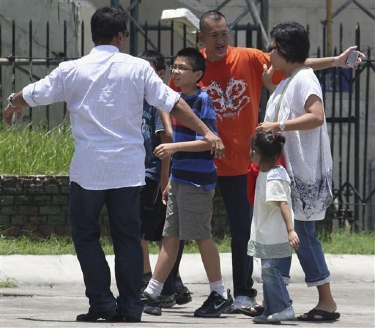 Hostage negotiators talk to foreign tourists taken hostage by former Senior Inspector Rolando Mendoza after securing their release at Manila's Rizal Park Monday, Aug. 23, 2010, in the Philippines. Mendoza, a dismissed policeman armed with an automatic rifle seized the bus in Manila Monday with 25 people aboard, most of them Hong Kong tourists, in a bid to demand reinstatement, police said. (AP Photo/Bullit Marquez)