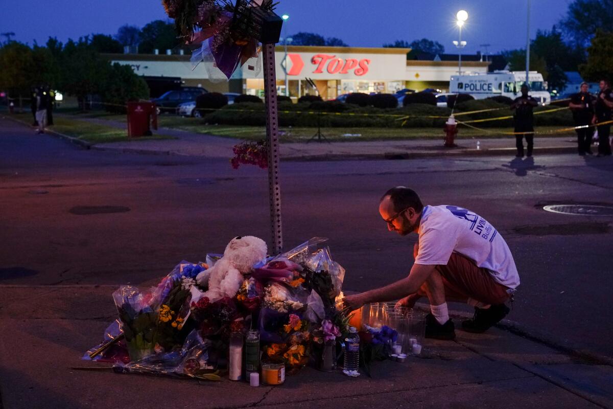 A man lights a candle at a street memorial outside Tops grocery store