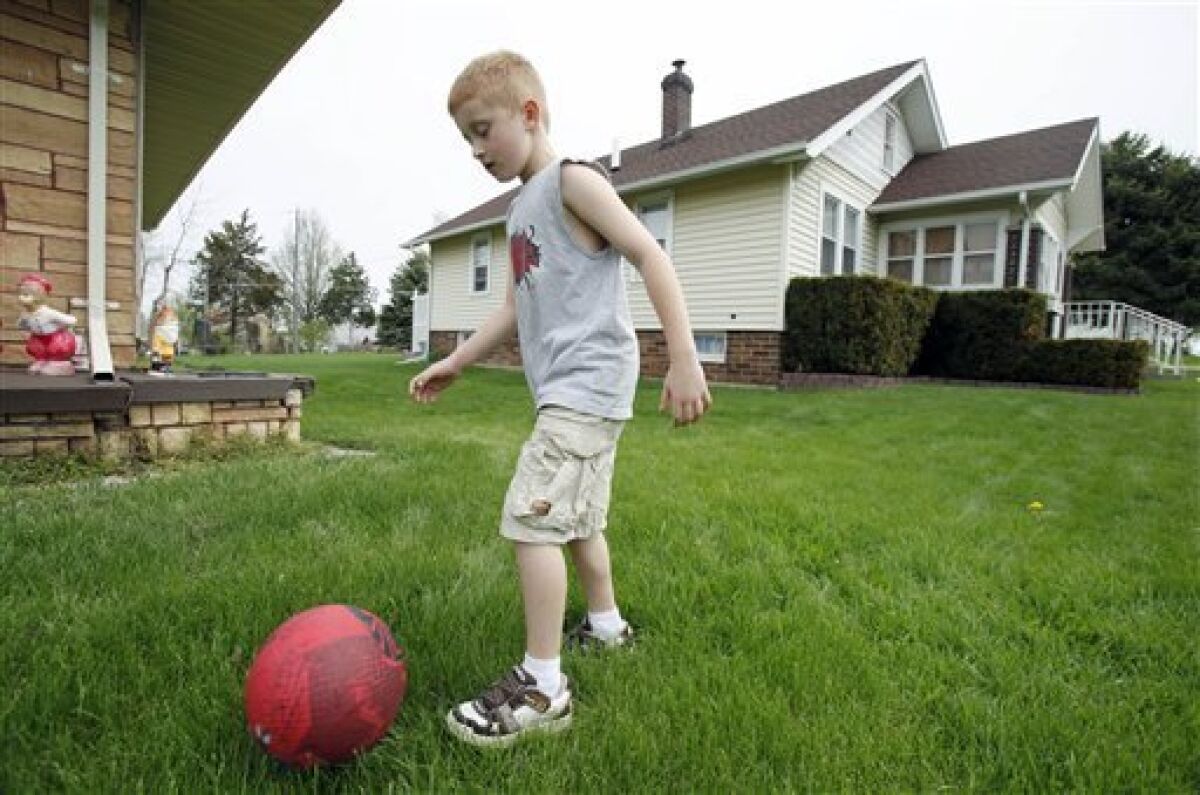 Eight-year old Kaydn Hainline, of Marshalltown, Iowa, kicks a ball in front of his grandfather's house, on a day off from school Monday, May 4, 2009, in Marshalltown, Iowa. Marshalltown officials have closed schools for the week due to several probable cases of swine flu in the city. (AP Photo/Charlie Neibergall)