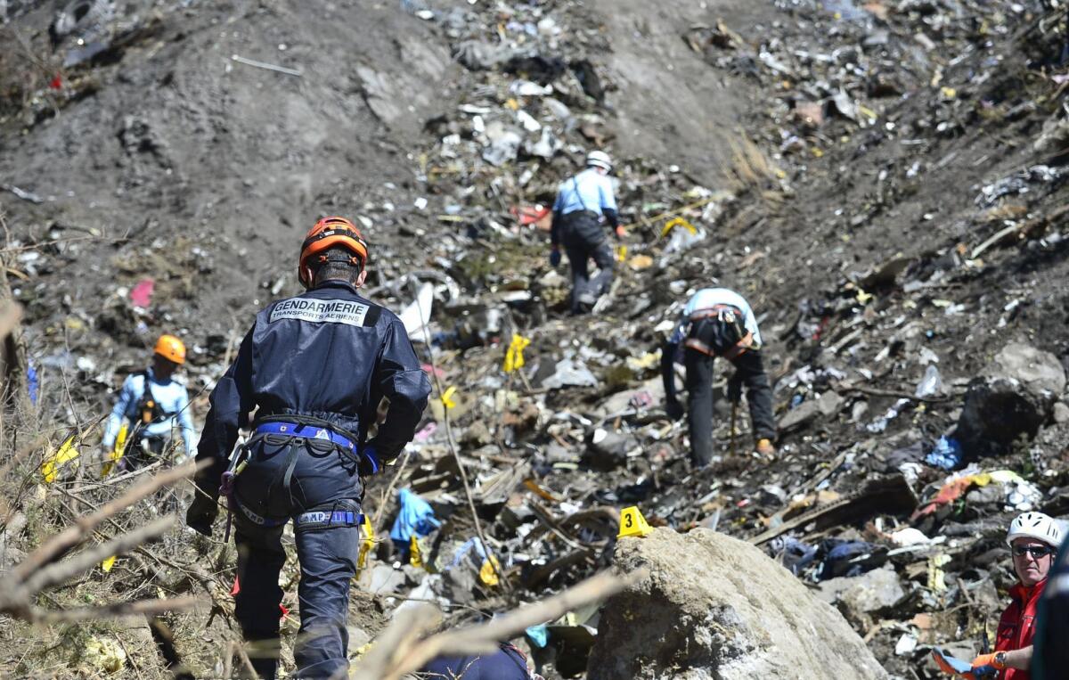 A handout photo taken on March 26, 2015 and released by the French Interior Ministry on March 27, 2015 shows a Gendarme from the Air Transport Gendarmerie (L) working at the crash site of the Germanwings Airbus A320 near Le Vernet, French Alps.