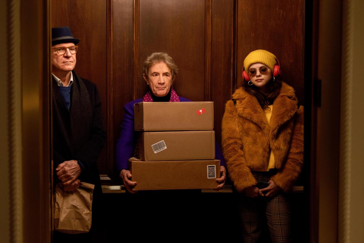 Charles, left, Oliver and Mabel stand side by side in a wood-paneled elevator.