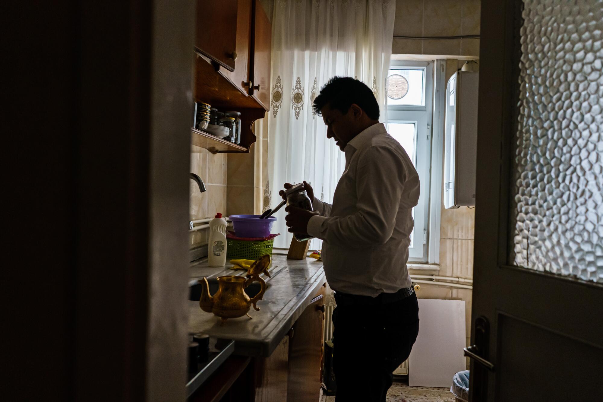 A man holds a jar near a kitchen counter