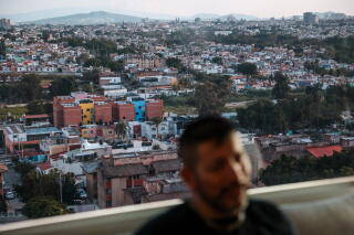 A blurry image of a man shown against a sprawling landscape of buildings and trees