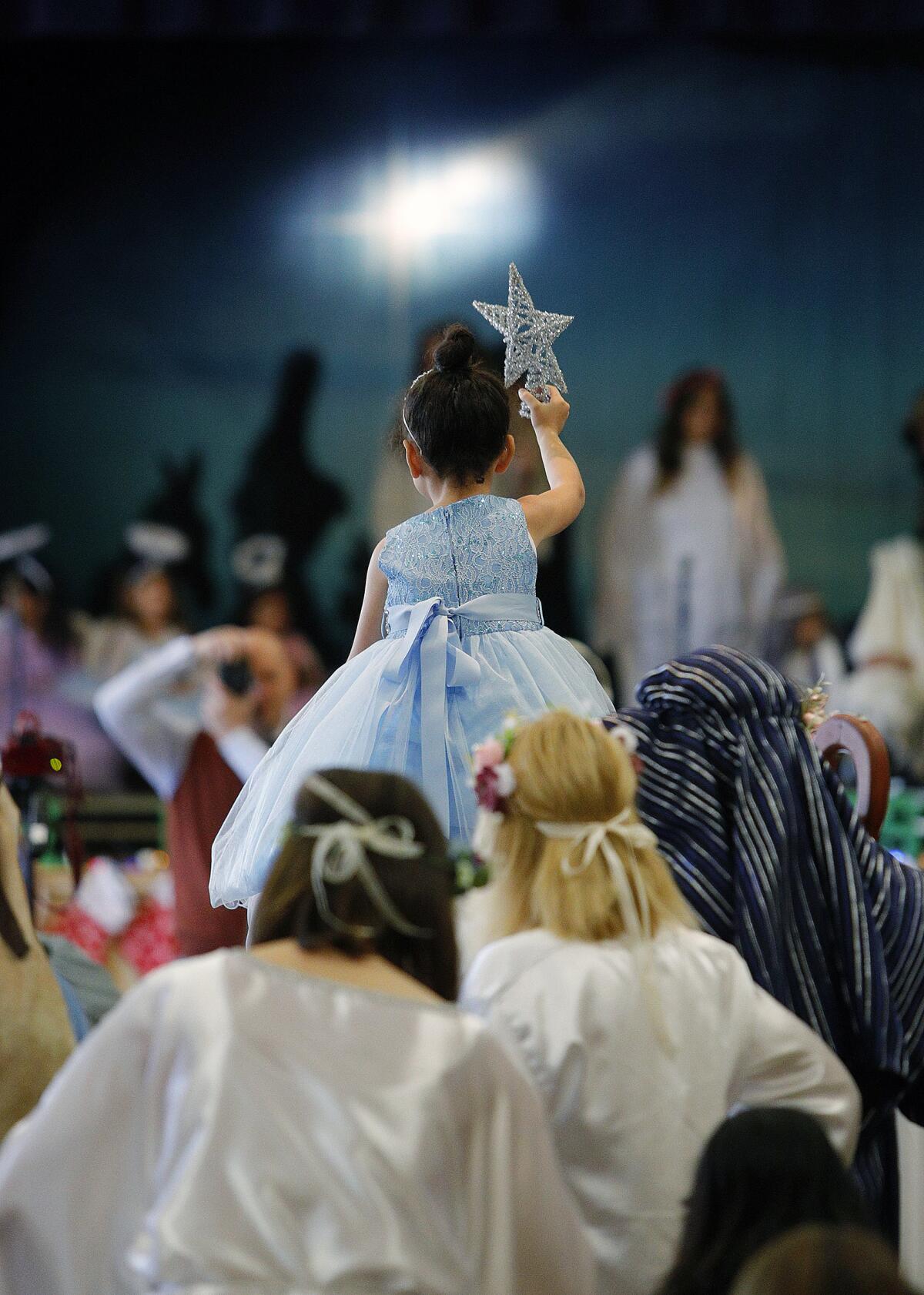 Amira Istanboullian, playing the Star of Bethlehem, rides high on the shoulders of a parent as she leads a group to the stage for the St. Robert Bellarmine Catholic School's holiday show called "Once Upon a Christmas," presented by the school's kindergarten class at St. John Paul II STEM Academy in St. Eleanor Hall on Monday. The story was told sequentially from the birth of Jesus to the arrival of angels by kindergartners from the school.